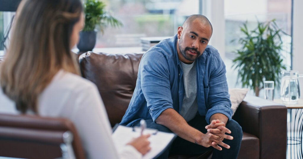 Adult man speaking with a mental health professional during a counseling session.